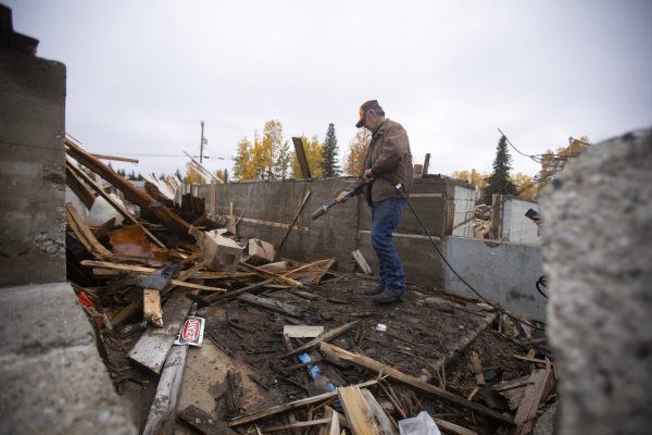 Fred McMillan, a residential school survivor, uses a propane torch to set the remains of the former Lower Post, B.C., residential school ablaze on Sep 29, 2021.